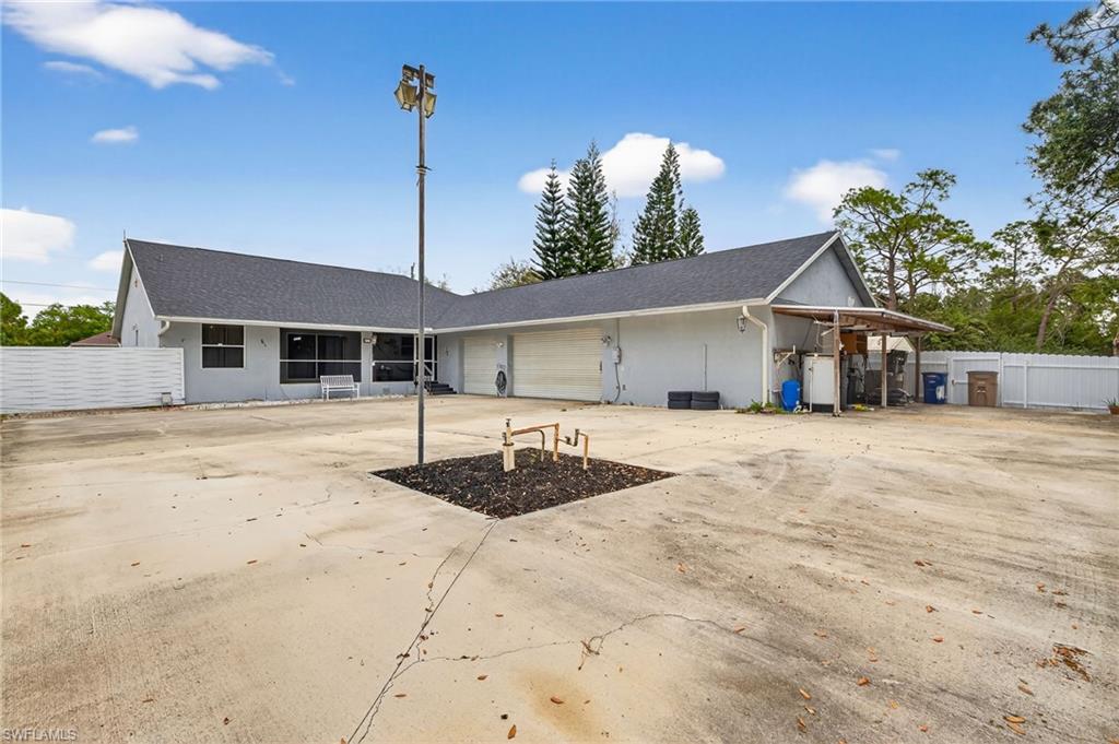 View of back of house featuring an attached garage, concrete driveway, stucco siding, and roof with shingles