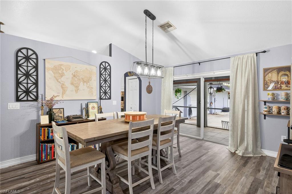 Dining space with lofted ceiling and dark wood-style floors