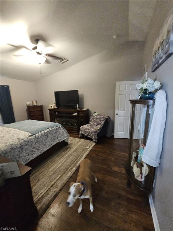 Bedroom with vaulted ceiling, dark wood-style flooring, and a ceiling fan