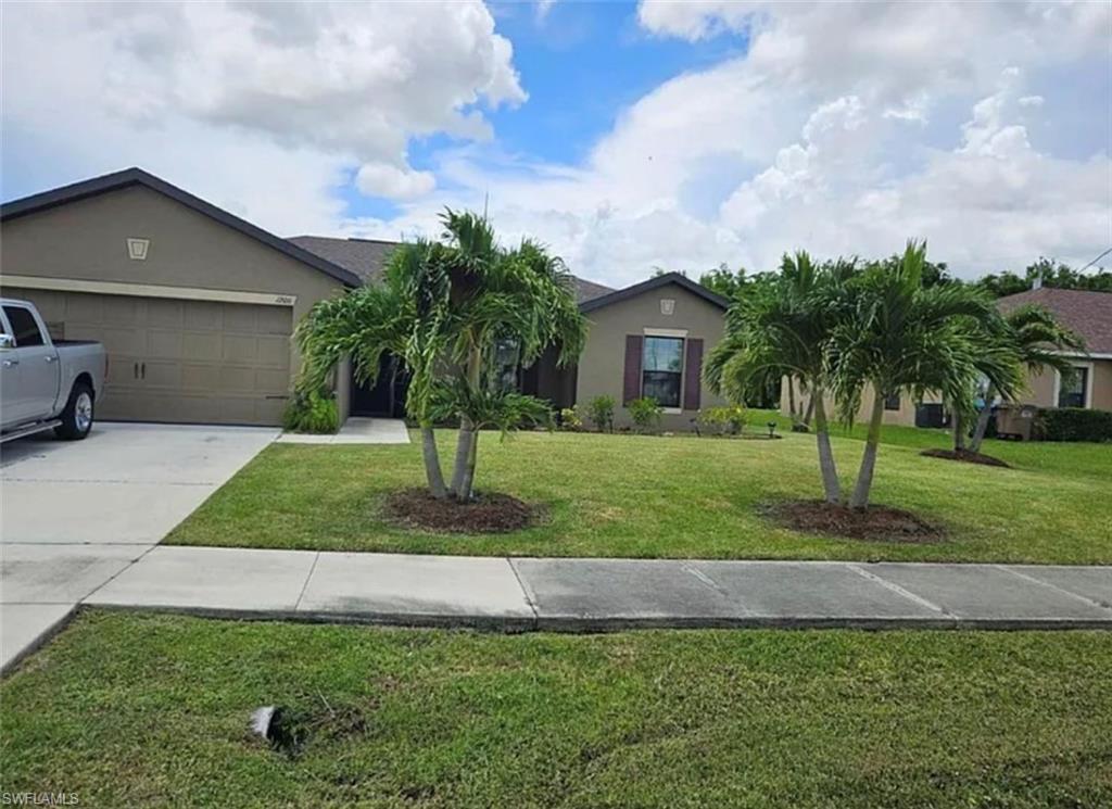 Ranch-style home featuring stucco siding, a front yard, driveway, and an attached garage