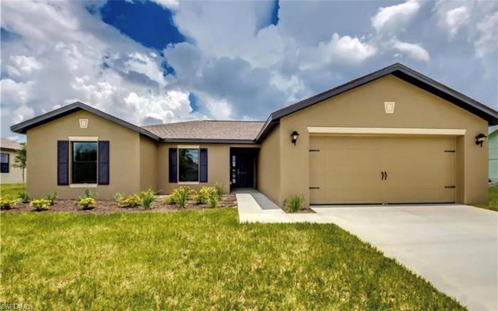 Single story home with stucco siding, an attached garage, a front yard, and driveway