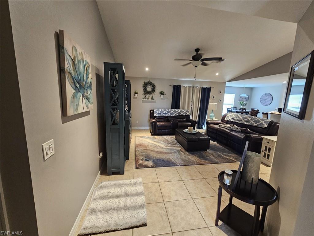 Living area featuring light tile patterned floors, lofted ceiling, ceiling fan, and recessed lighting