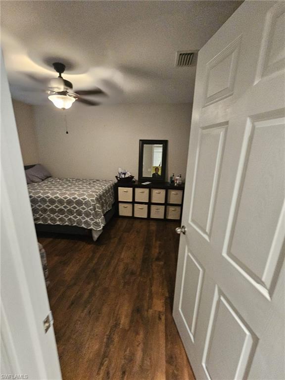 Bedroom with dark wood-type flooring, a textured ceiling, and a ceiling fan