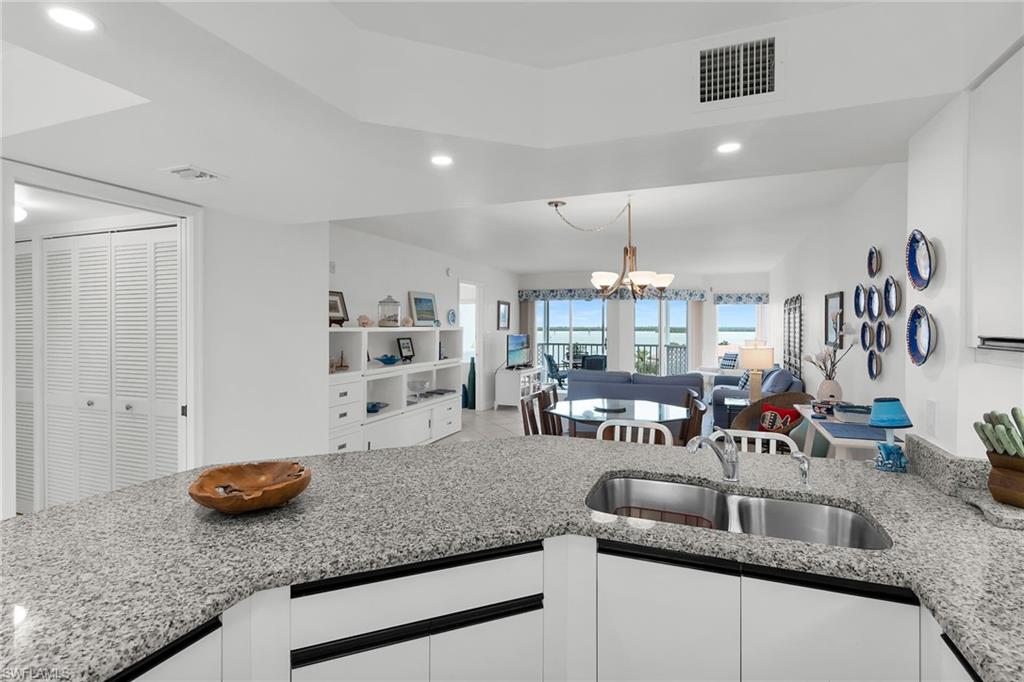 Kitchen featuring light stone countertops, white cabinetry, and open floor plan