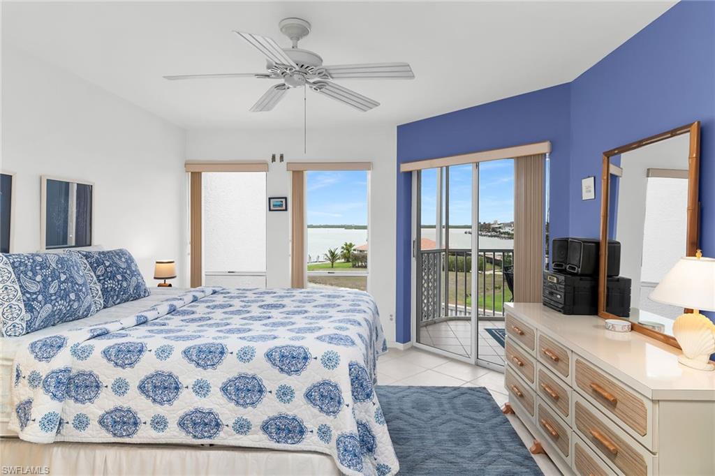 Bedroom featuring a water view, a ceiling fan, light tile patterned flooring, and access to exterior
