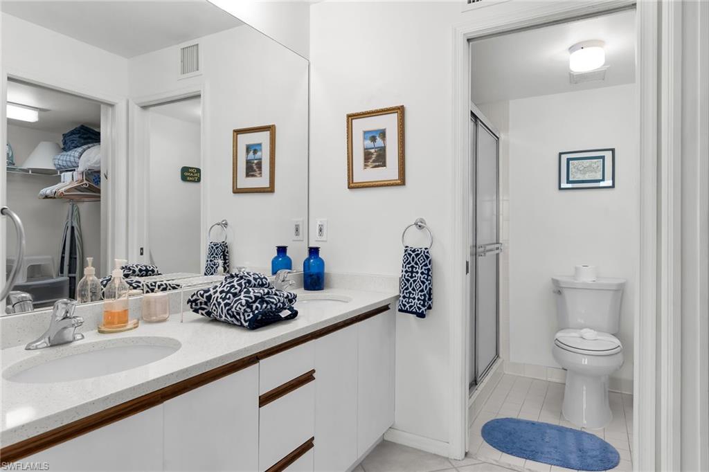 Bathroom with double vanity, a shower stall, and light tile patterned flooring