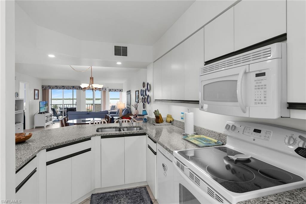 Kitchen featuring white appliances, a chandelier, open floor plan, and white cabinets