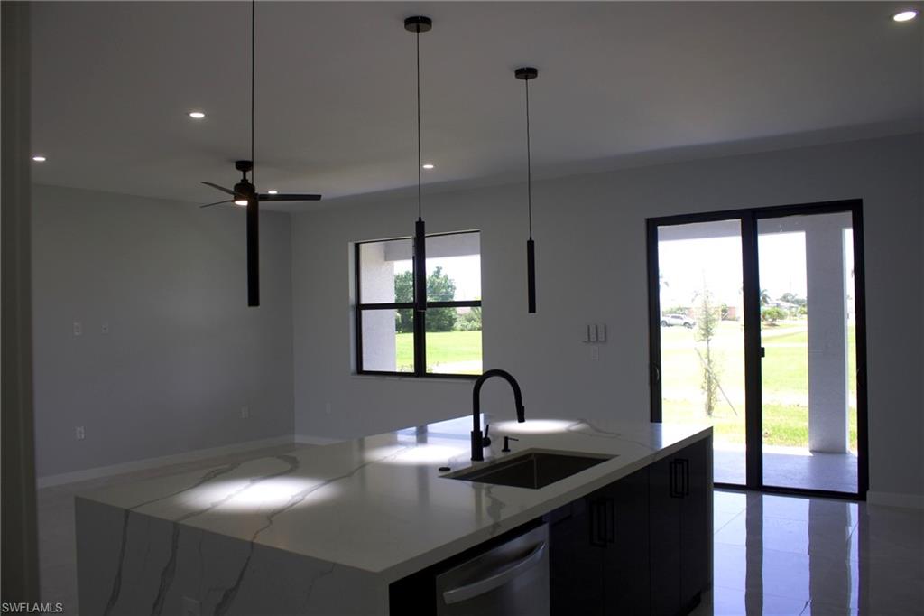 Kitchen featuring light stone countertops, an island with sink, stainless steel dishwasher, modern cabinets, and dark cabinets
