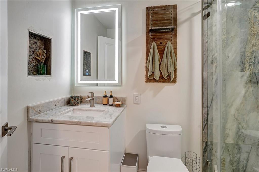 Full bath featuring toilet, vanity, and a shower stall