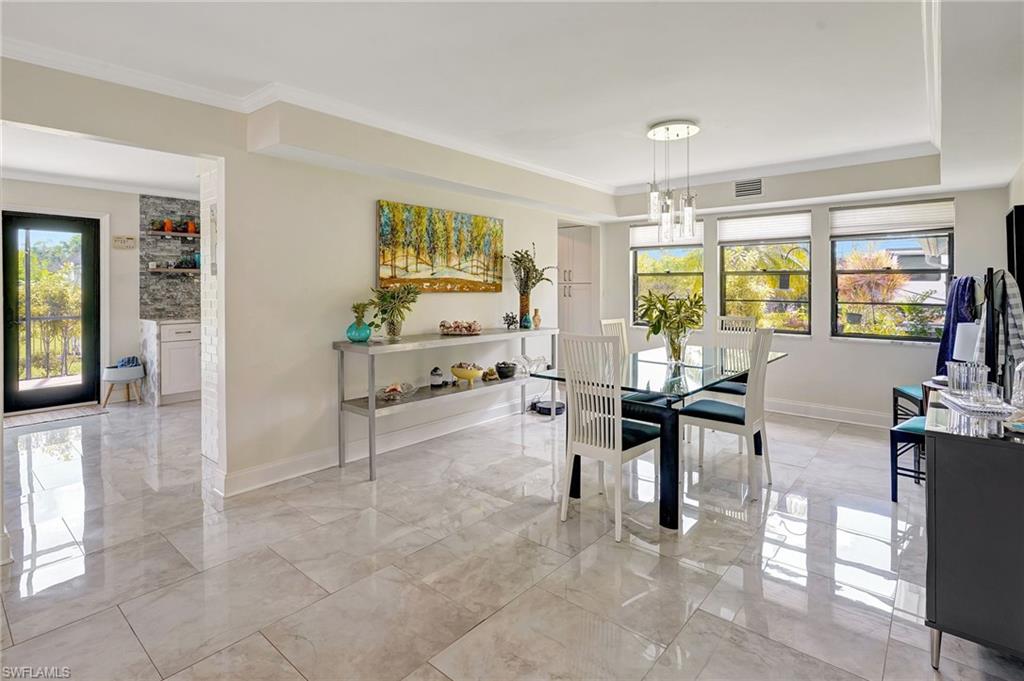 Dining area with marble finish floor and ornamental molding