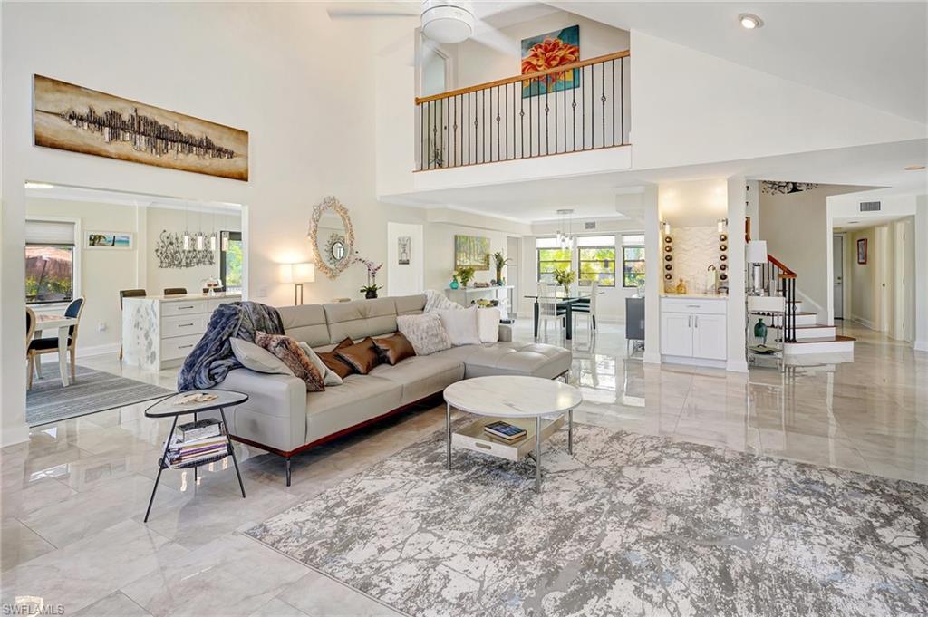 Living area featuring  marble finish floor, ceiling fan, stairs, and a towering ceiling