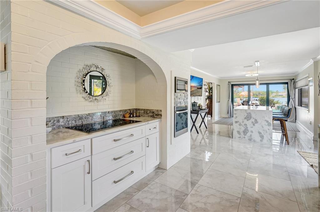 Kitchen featuring white cabinets, marble finish floor, ornamental molding, stainless steel oven, and black electric stovetop