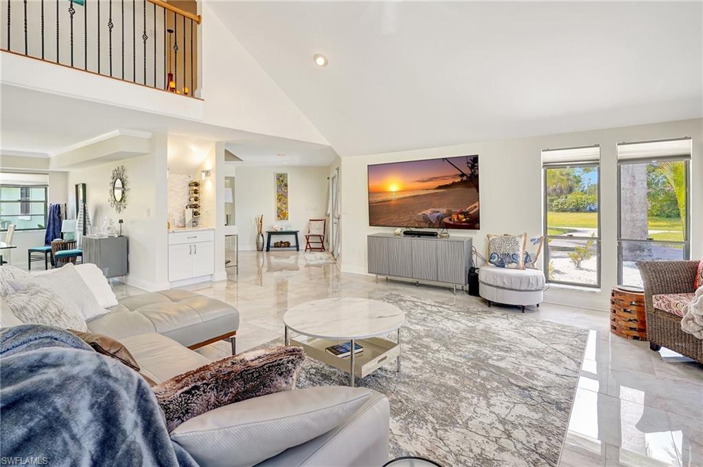 Living room with marble finish floor, a towering ceiling, and recessed lighting
