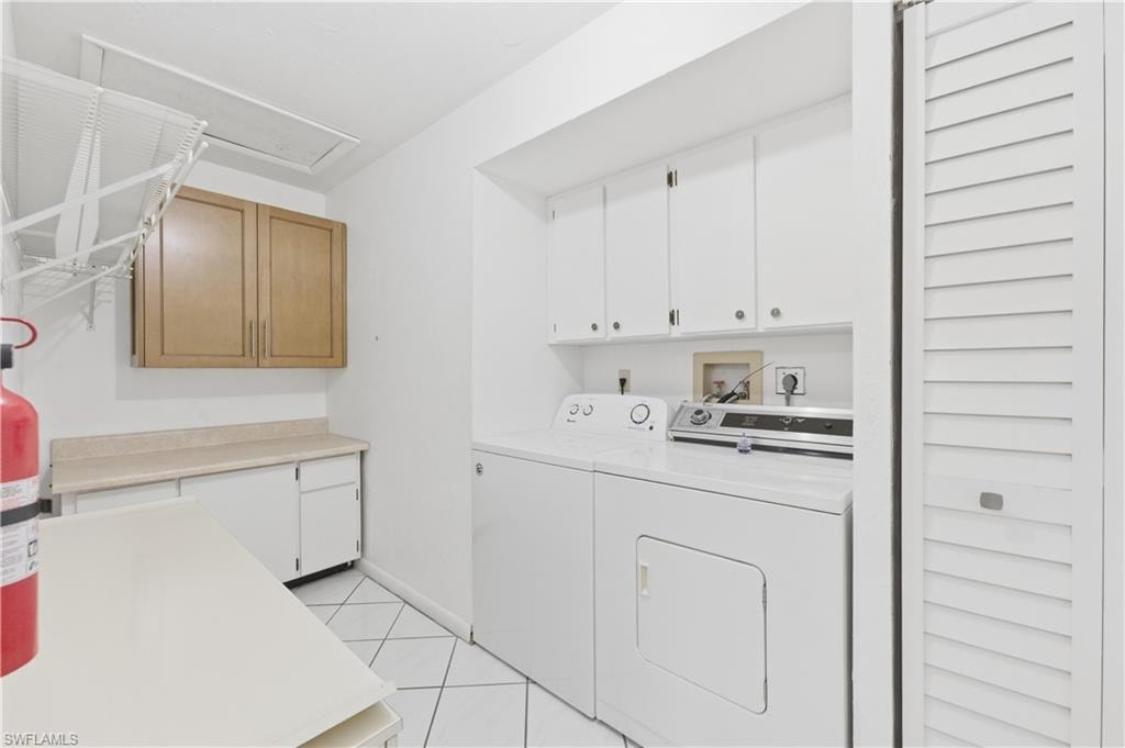 Laundry room with cabinet space, independent washer and dryer, and light tile patterned floors