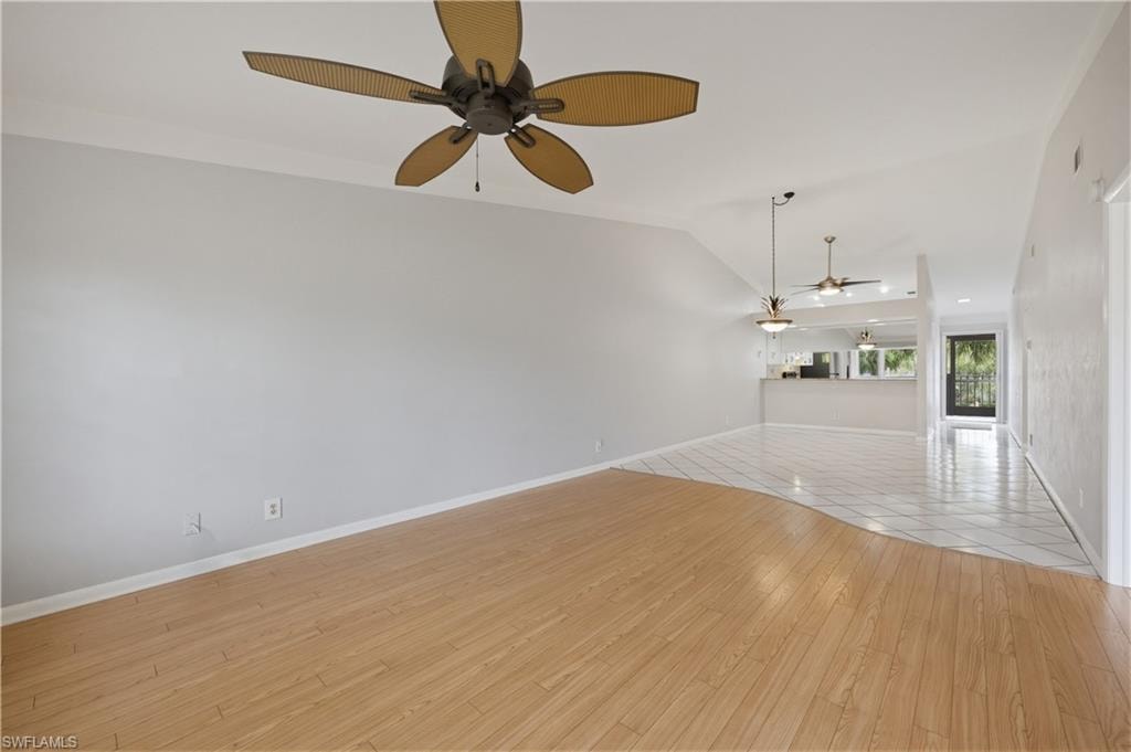 Unfurnished living room featuring light wood finished floors, ceiling fan, and vaulted ceiling