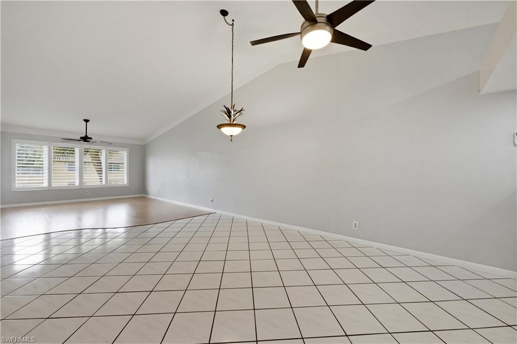 Great room featuring a ceiling fan, vaulted ceiling, and light tile patterned floors