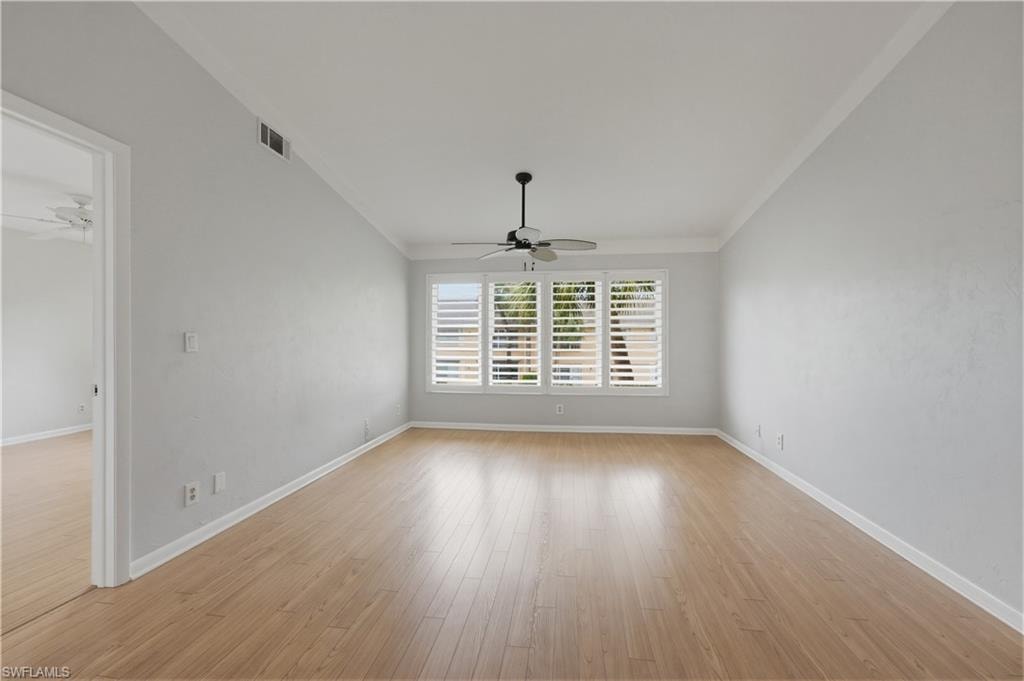 Living room with ceiling fan, light wood finished floors, and crown molding