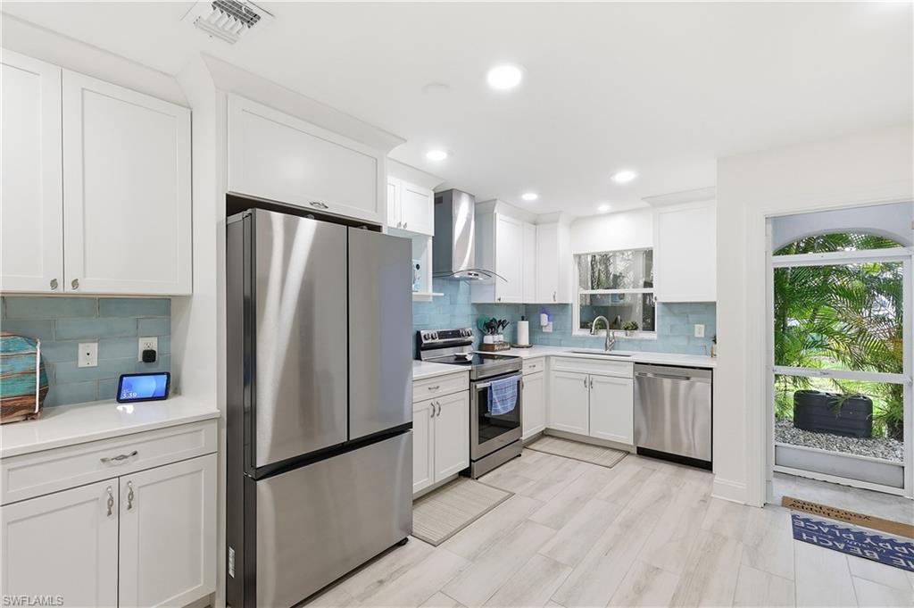 Kitchen with stainless steel appliances, white cabinets, backsplash, recessed lighting, and light stone counters
