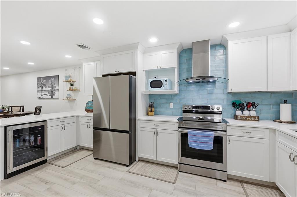 Kitchen with stainless steel appliances, white cabinets, wine cooler, open shelves, and recessed lighting