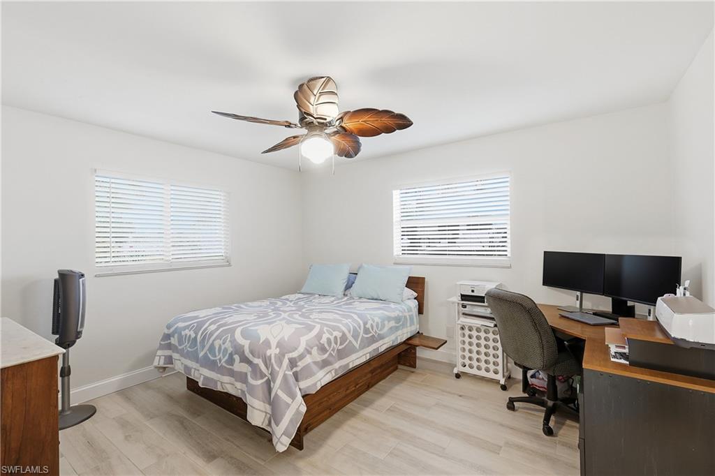 Bedroom with light wood-style flooring, a desk, and ceiling fan