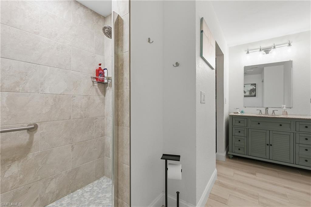 Full bath featuring vanity, walk in shower, and light wood-style flooring