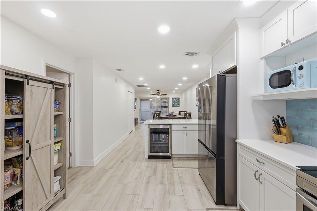 Kitchen featuring wine cooler, white cabinetry, freestanding refrigerator, a peninsula, and a barn door