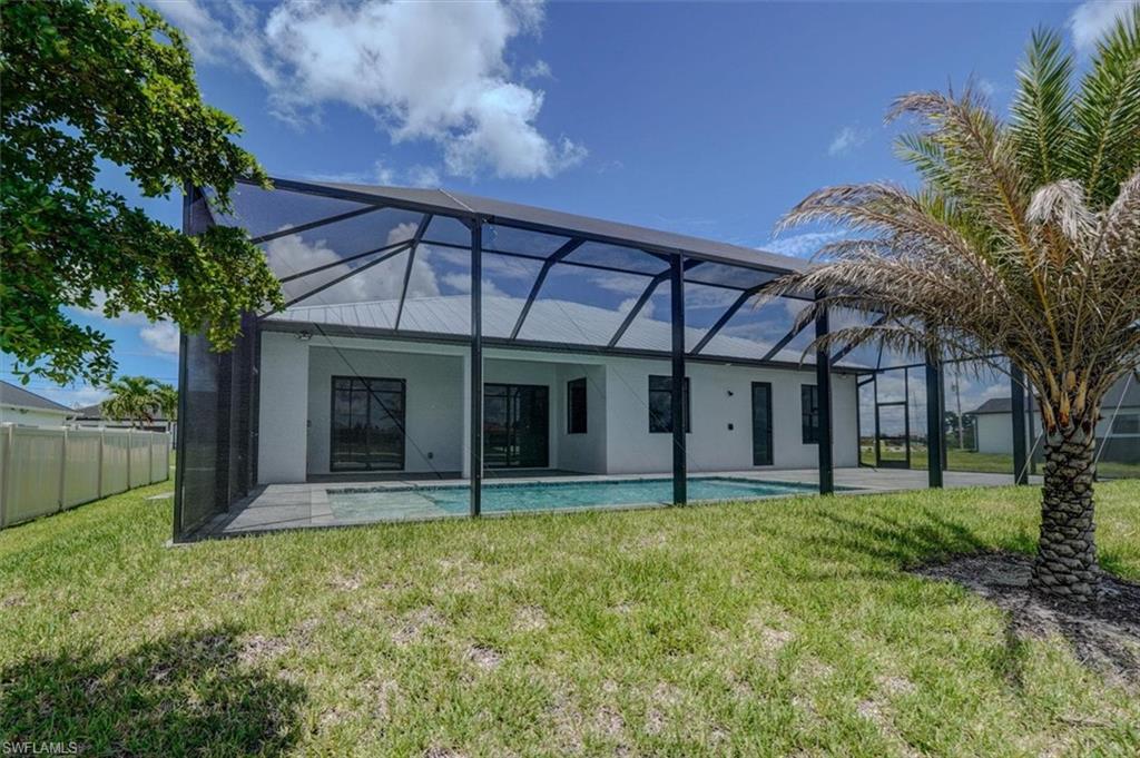 Back of property with a lawn and a lanai