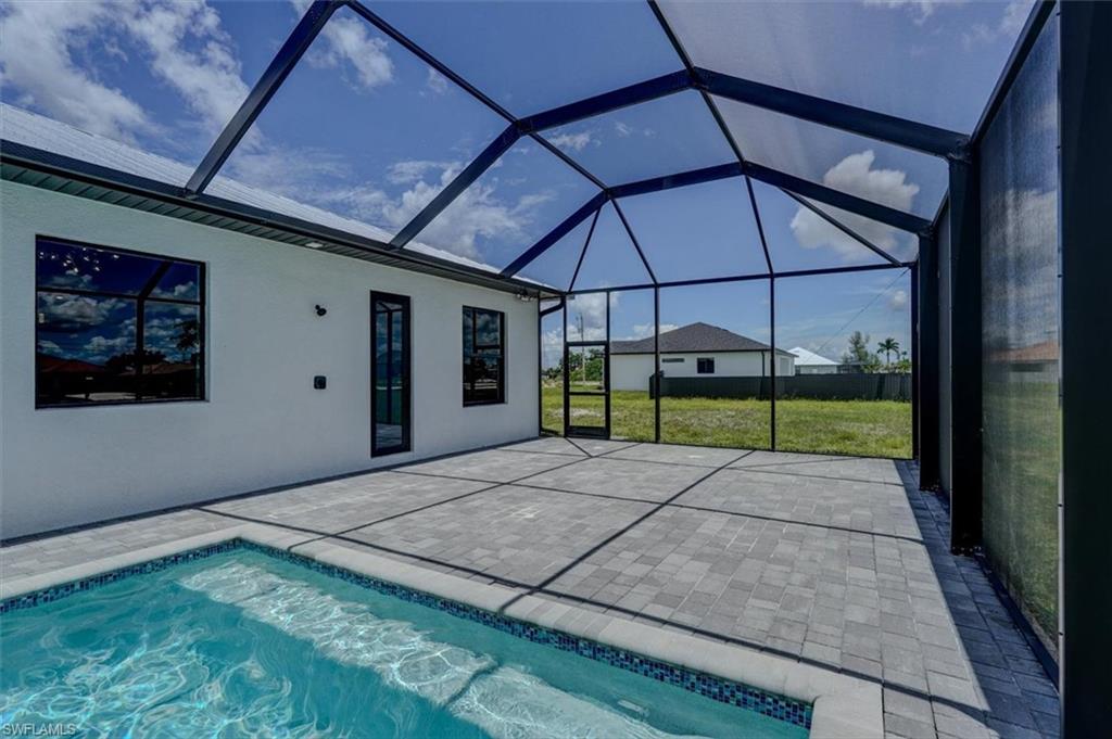 View of swimming pool featuring a patio, a yard, and glass enclosure