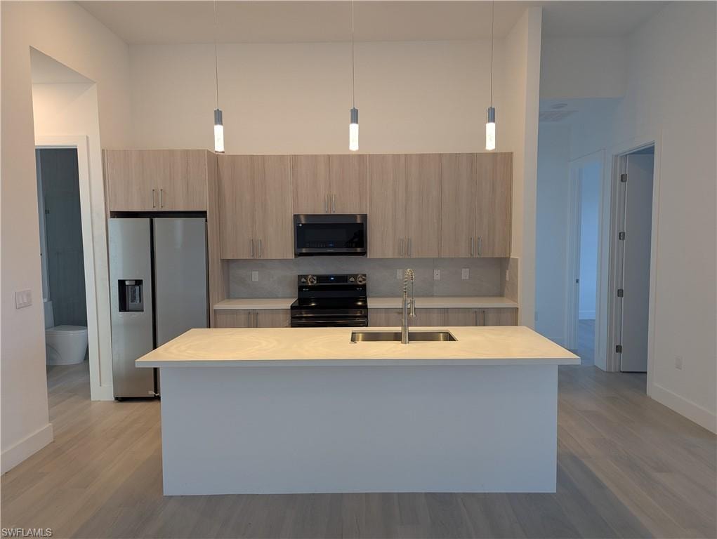 Kitchen with tasteful backsplash, sink, stainless steel appliances, and decorative light fixtures