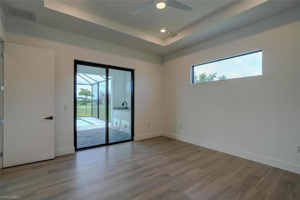 Spare room featuring wood-type flooring, a healthy amount of sunlight, ceiling fan, and a raised ceiling