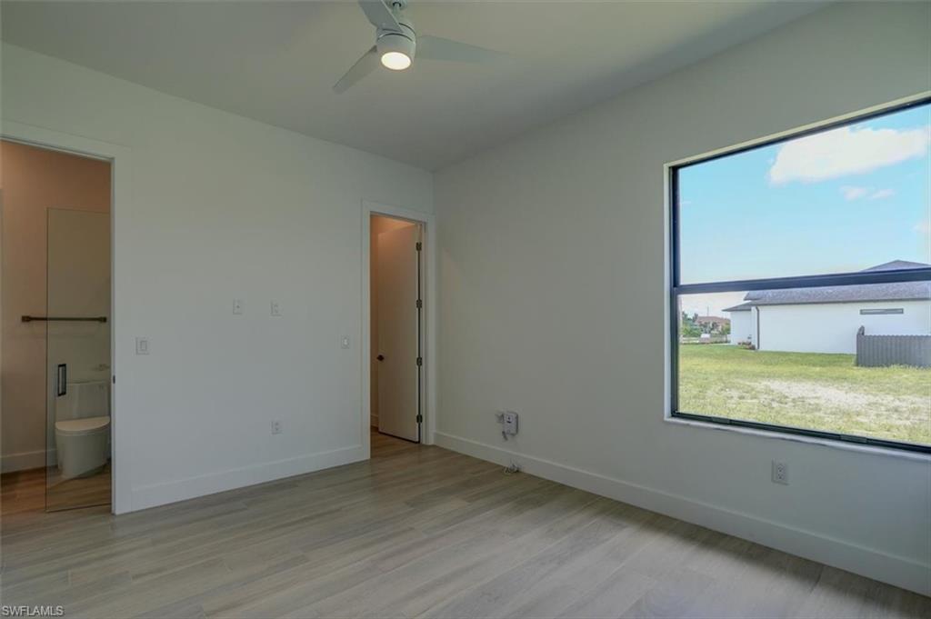 Unfurnished bedroom with light hardwood / wood-style flooring, connected bathroom, and ceiling fan