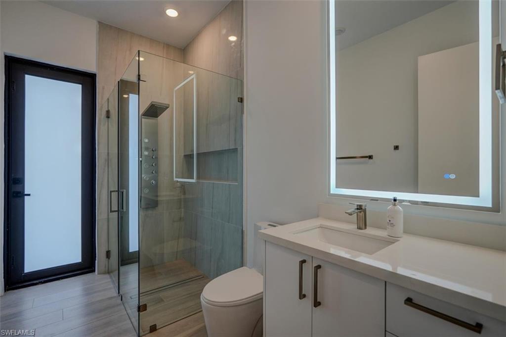 Bathroom featuring vanity, an enclosed shower, and toilet