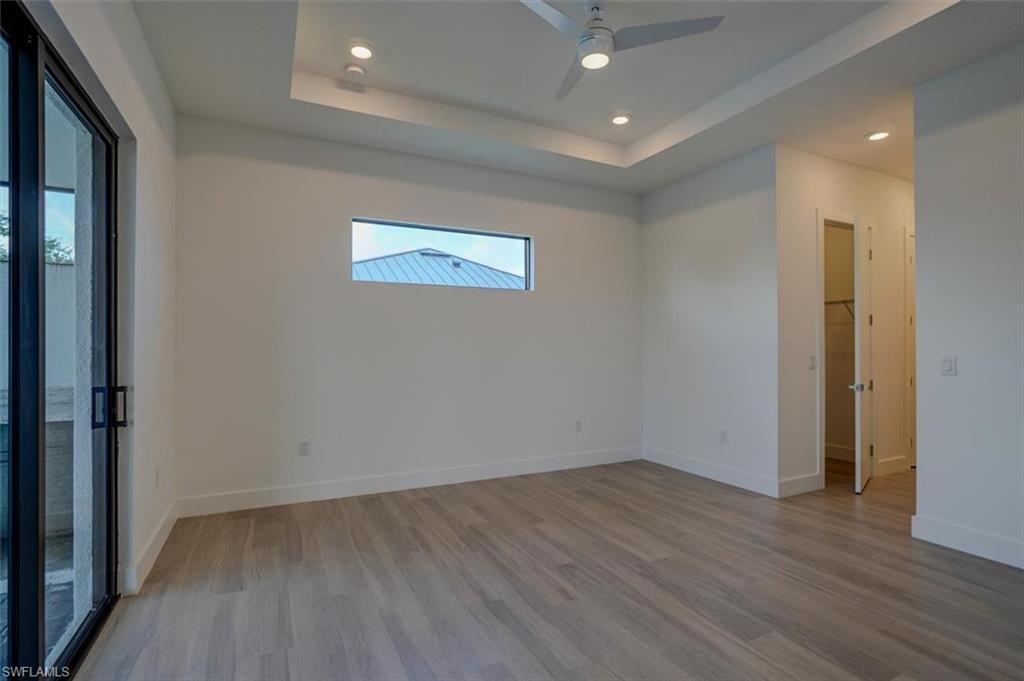 Spare room featuring ceiling fan, a tray ceiling, and light hardwood / wood-style flooring