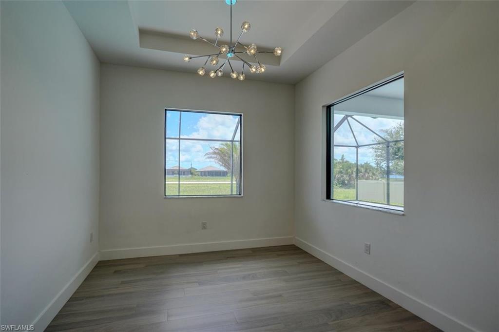 Spare room featuring wood-type flooring, a raised ceiling, and a chandelier