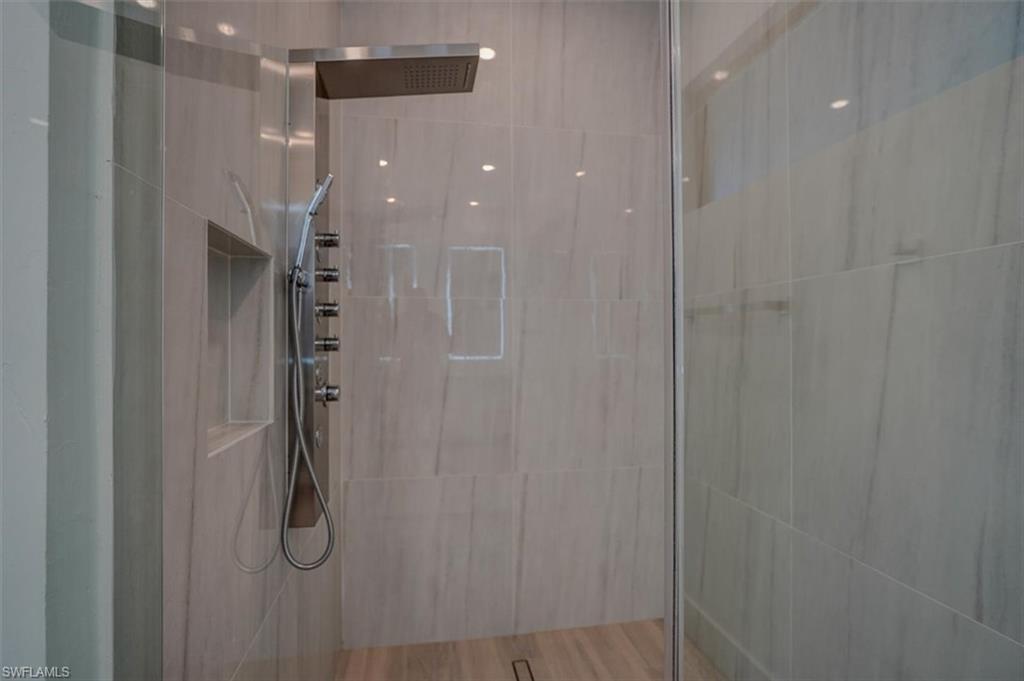 Bathroom featuring tiled shower, hardwood / wood-style floors, and tile walls