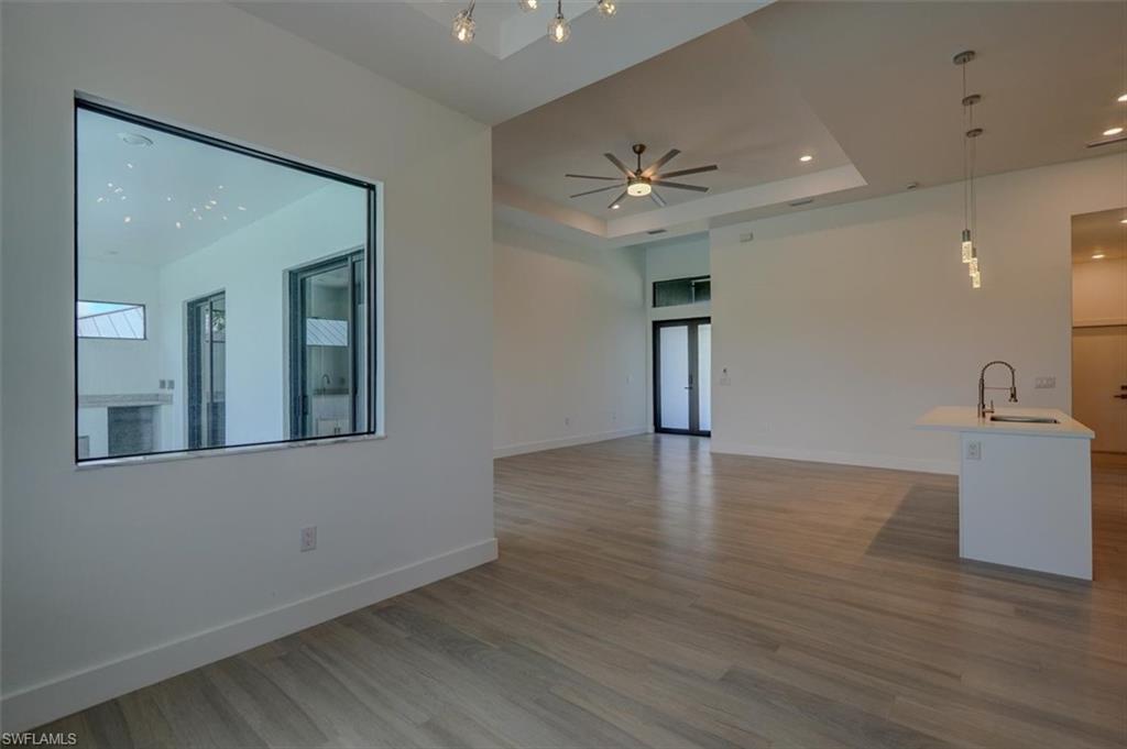 Spare room featuring a tray ceiling, sink, french doors, light wood-type flooring, and ceiling fan