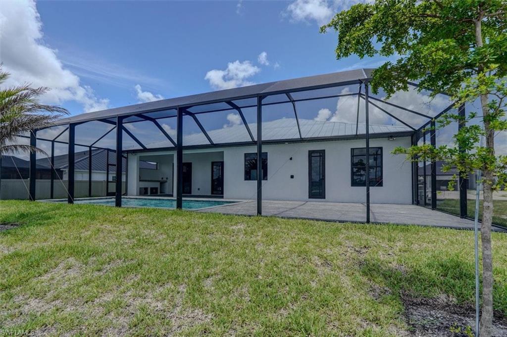 Rear view of house with a yard, a patio, and a lanai
