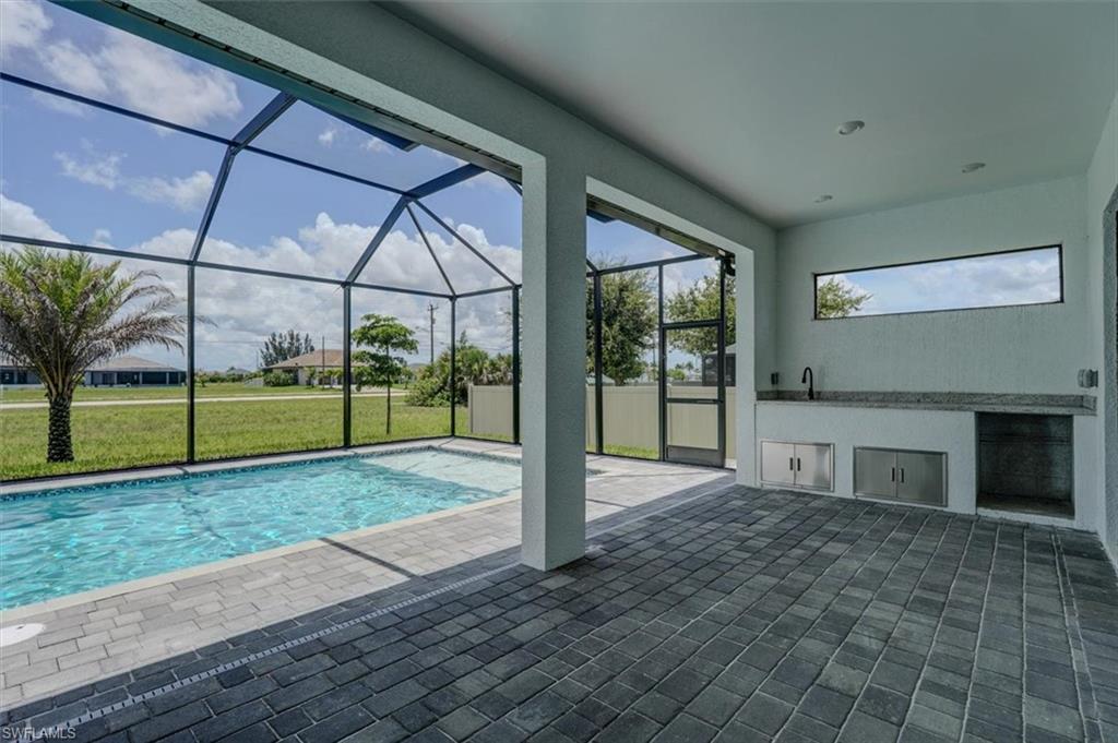 View of pool featuring a lawn, a patio, a lanai, and sink