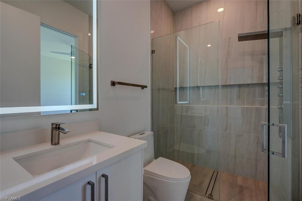 Bathroom with vanity, walk in shower, and toilet