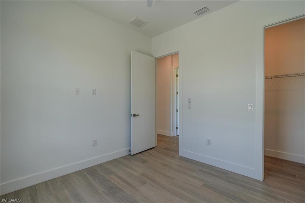 Unfurnished bedroom featuring a closet, a spacious closet, and hardwood / wood-style flooring