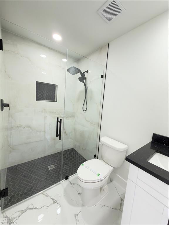 Full bathroom featuring a marble finish shower, vanity, and marble look tile flooring