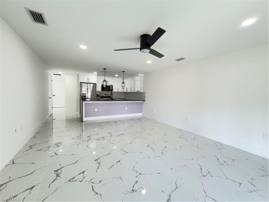 Unfurnished living room featuring a ceiling fan, recessed lighting, and light marble finish floors