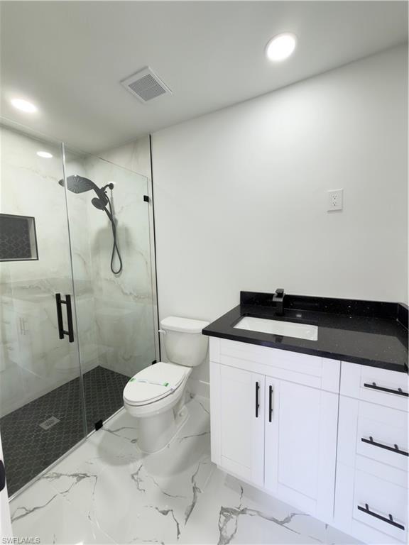 Full bath with vanity, a marble finish shower, and recessed lighting