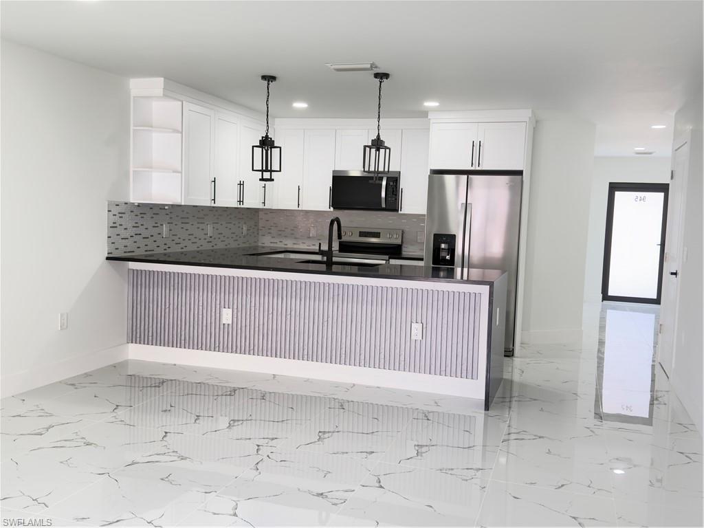 Kitchen featuring dark stone counters, a peninsula, open shelves, stove, and white cabinetry