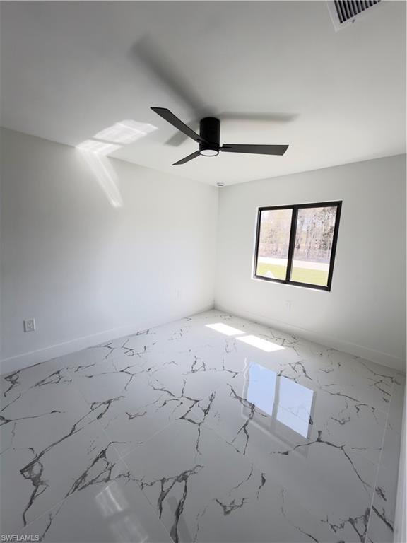 Spare room featuring light marble finish floors and ceiling fan