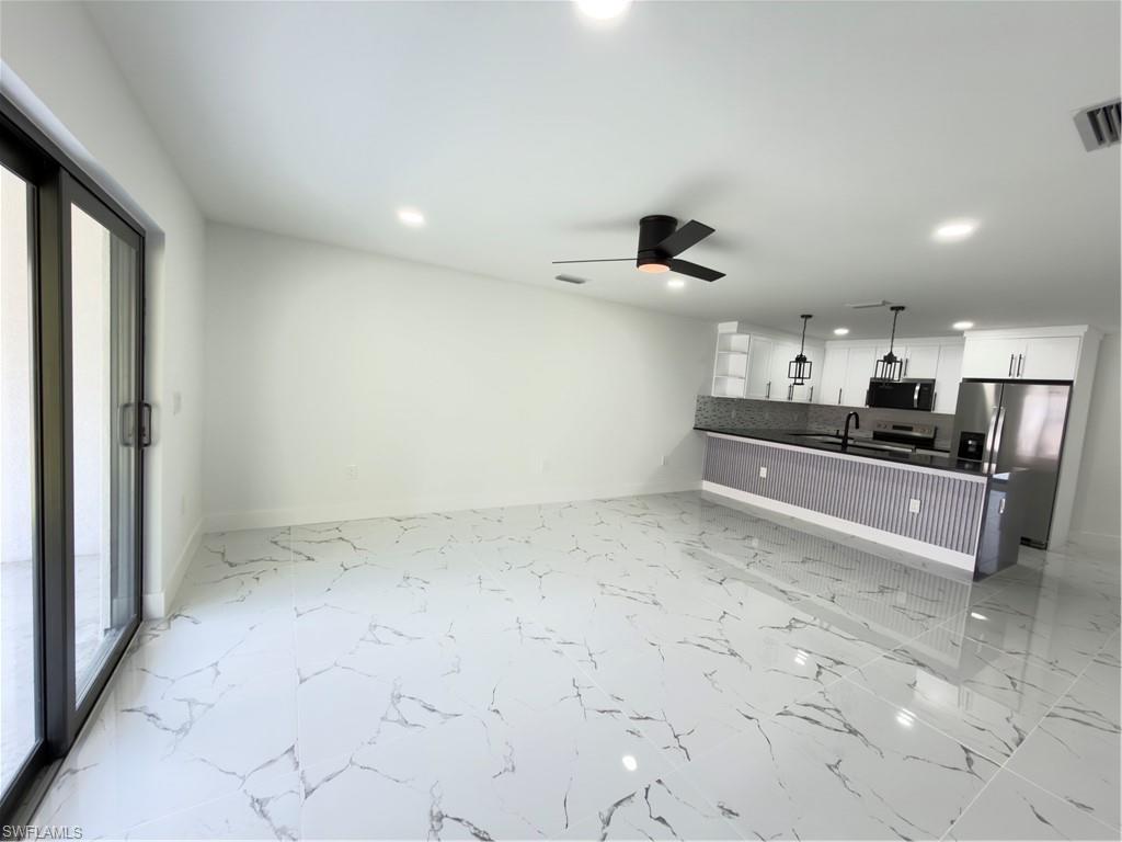 Kitchen with open floor plan, refrigerator, a ceiling fan, and white cabinets