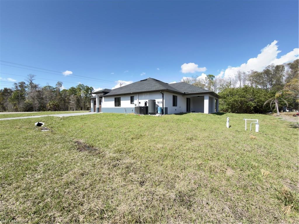 Rear view of property with a lawn, stucco siding, and view of wooded area