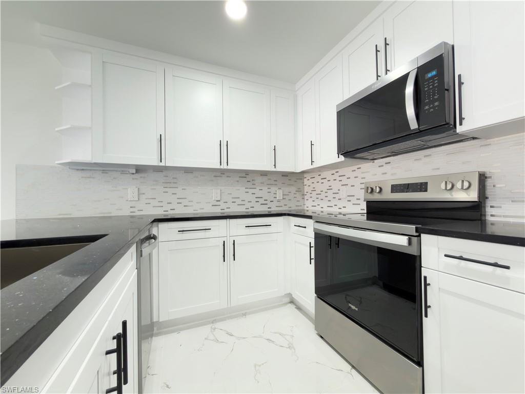 Kitchen featuring stainless steel appliances, open shelves, and white cabinetry