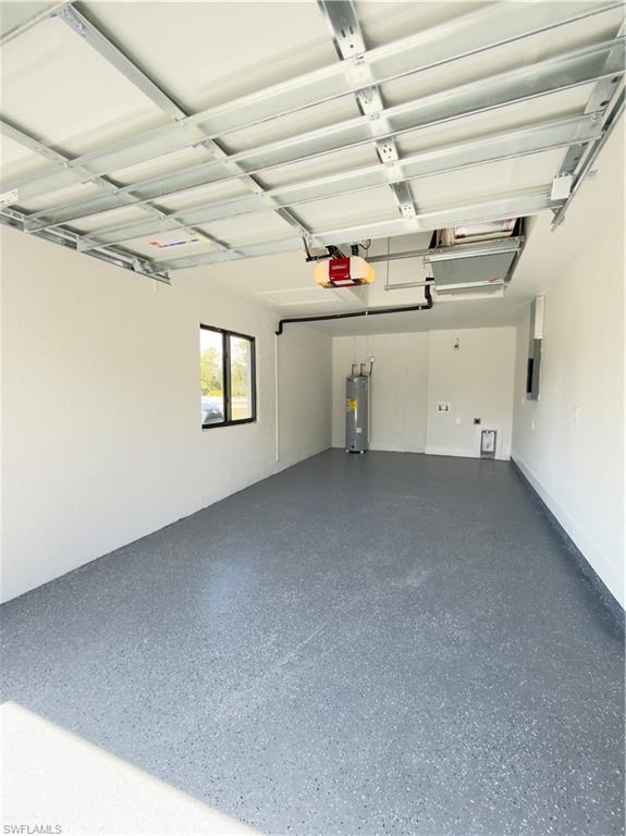 Garage featuring water heater, electric panel, and a garage door opener