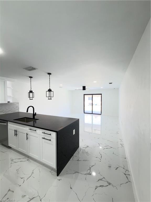 Kitchen featuring white cabinets, open shelves, dishwasher, dark stone countertops, and hanging light fixtures